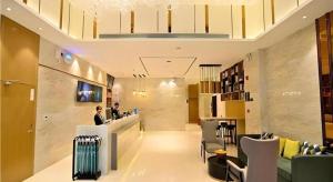 City Comfort Inn Kunming High-speed Railway South Station 7th Street Area في كونمينغ: لوبي محل فيه رجل واقف عند كاونتر