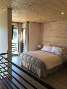 1 dormitorio con 1 cama grande y pared de madera en Loft Pucon, en Pucón
