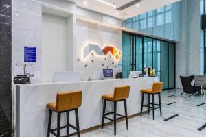 a lobby with a counter with two stools at Borrman Hotel Ji'nan Aoti Center East Provincial Hospital in Jinan