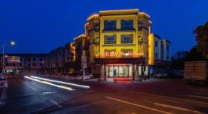 a tall yellow building on a city street at night at Shell Hotel Changzhou North Railway Station Global Harbor Metro Station in Changzhou