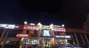 a building with cars parked in front of it at night at Shell Hotel Shanghai Jinshan Wanda Plaza in P'ai-ts'ang
