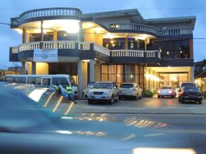 a parking lot with cars parked in front of a building at Bella Casa Hotel in Monrovia
