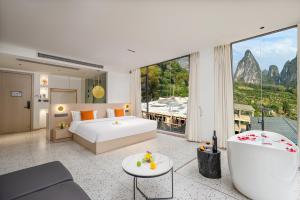 a bedroom with a white bed and a large window at Yangshuo Yundu Panoramic Luxury Hotel in Xingping