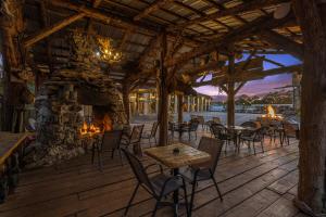 eine Terrasse mit Tischen und Stühlen und einem Steinkamin in der Unterkunft Stonegate Lodge Bear's Den Kitchen, Pool, Firepit, WIFI ,Smart TVs in Eureka Springs