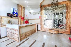 Un uomo in piedi al bancone in una stanza con uno specchio di Hotel O by OYO MM Yellowuds ad Amritsar