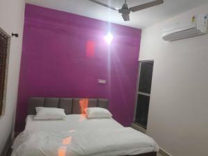 a purple wall in a room with a bed at Hotel O Green Villa in Bilāspur