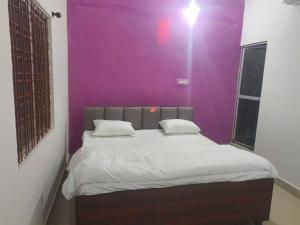 a bed in a room with a purple wall at Hotel O Green Villa in Bilāspur