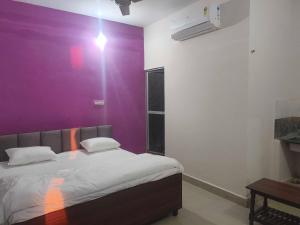 a bedroom with a purple wall and a bed at Hotel O Green Villa in Bilāspur