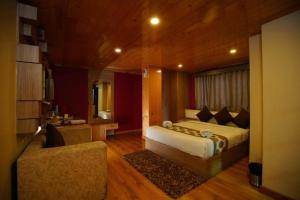 a bedroom with a bed and a chair in a room at Retreat Hotel Queen in Darjeeling