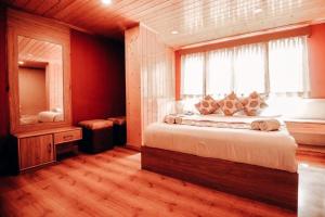 a bedroom with a large bed with a window at Retreat Hotel Queen in Darjeeling +3 photos