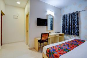 a bedroom with a bed and a desk and a mirror at FabHotel Tap Inn in Bengaluru