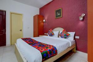 a bedroom with a large bed with a red wall at FabHotel Tap Inn in Bengaluru
