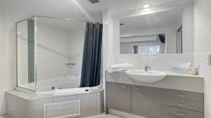 un bagno bianco con lavandino e vasca di Ocean Jewel a Ettalong Beach