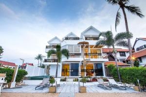 a large white building with chairs and palm trees at B1 Beachfront Apartments in Bophut 
