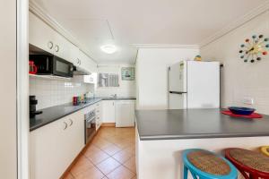 a kitchen with white cabinets and a refrigerator at Shoreline Apartments - Unit 9a in Bargara
