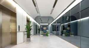 Atour X Hotel Qingdao Shilaoren Beach Exhibition Center Metro Station في تشينغداو: ممر مبنى بجدران زجاجية ومنحوتات