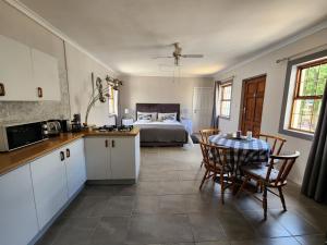 a kitchen with a table and a bedroom with a bed at Alcyone in Gqeberha