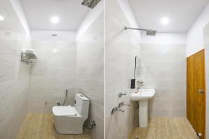 a white bathroom with a toilet and a sink at FabHotel Rubicon in Faridabad +17 photos