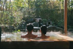 two people sitting in a bath tub in a fountain at 四季の宿 明翠 in Kirishima