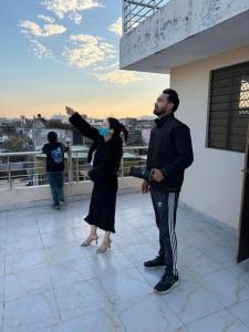 斋浦尔The Pink Nest - Backpackers Abode的站在屋顶上的男人和女人