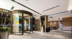 Echarm Hotel Wuhan Hankou Railway Station Zhuyeshan Metro Station في ووهان: ردهة مبنى بها نوافذ زجاجية ونباتات