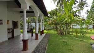 un patio de una casa con árboles y césped en Lucas, en Bentota