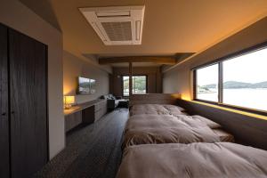 een slaapkamer met 3 bedden en een groot raam bij 中尾甚六hotel in Karatsu