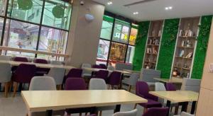 Lavande Hotel Shenzhen East Gate Wanxiang City Guomao Metro Statipn في شنجن: مكتبة بها طاولات وكراسي وجدران خضراء