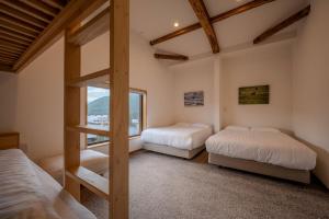 Dos camas en una habitación con ventana. en Dennojo, en Nozawa Onsen