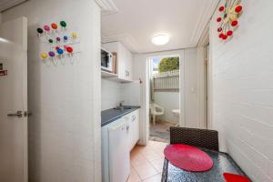 een keuken met een gootsteen en een rode kruk in een kamer bij Shoreline Apartments - Unit 9b in Bargara