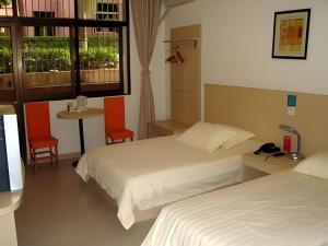 Jinjiang Inn Shaoxing Shengli West Road Luxun Hometown في شاوكسينج: غرفة فندقية تحتوي على سريرين وطاولة وكراسي