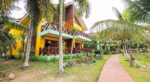 OYO 920 Saensukkho Hotel And Resorts في Ban Hua Doi: منزل اصفر امامه اشجار النخيل