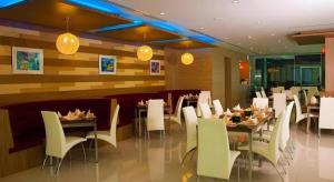 a restaurant with tables and white chairs and lights at V-One Hotel Korat in Ban Khok Phai (1)