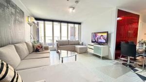 Una sala de estar con un sofá y un televisor. en Ausmine Sydney CBD 2Bedroom Apt, en Sídney