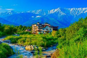 a house on a hill next to a river at Aachman Riviera Resort Dharamshala - A river facing rooms with balcony #rivertouch #snowfacing #centrally AC #terrace cafe restaurant #parking in Dharamshala