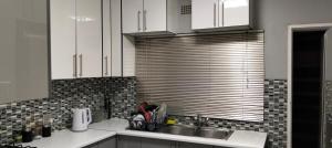 a kitchen with white cabinets and a sink and a window at Diamondfield trading guesthouse in Kimberley
