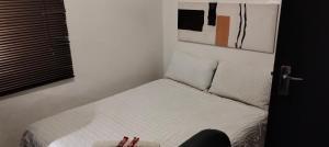 a small bedroom with a bed with white sheets and pillows at Diamondfield trading guesthouse in Kimberley