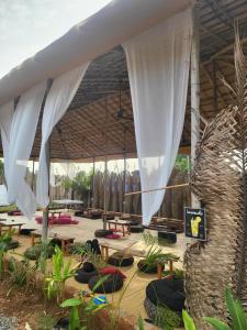 a pavilion with tables and white curtains and a group of tables at REWOGA Gaia Resort - Luxury Rooms with Open-Air Shower in Arambol