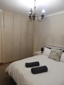 a bedroom with a white bed with two pillows on it at Mountain Zebra Cottage in Graaff-Reinet +7 photos