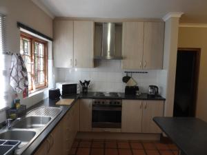 a kitchen with a sink and a stove top oven at Mountain Zebra Cottage in Graaff-Reinet
