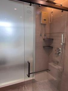um chuveiro com porta de vidro em um banheiro em Beijing Daxing Apartment em Ban Doung