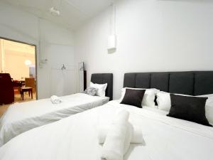 #SE Cozy&Warm 3Bedroom HomeStay 10PAX by S&T Homez في سِريمبان: سريرين في غرفة مع ملاءات بيضاء ووسائد سوداء