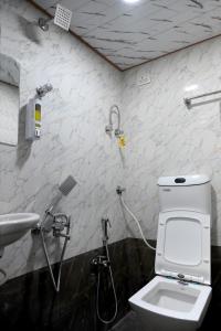 a bathroom with a shower and a toilet and a sink at Hotel Bhagirath in Mumbai