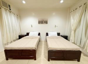 伊洛伊洛Chez Mathilds的配有2张床的白色墙壁和窗户客房