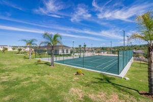 Cedar Square Apartment في Trevallyn: ملعب تنس في ساحة بها أشجار نخيل