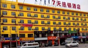 a yellow building with cars parked in front of it at 7 Days Inn Hohhot Kaitai Market in Hohhot