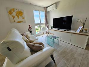 a living room with a white couch and a flat screen tv at Horizon Magellan - Grand T3 de 86m2 - Sainte-Marie in Sainte-Marie