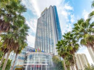 Xin Sheng Da Hong Sheng International Hotel في كونمينغ: مبنى شاهق أمامه أشجار النخيل