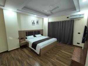 Un dormitorio con una cama y un televisor. en Expo Residency Inn, en Jāmb 3 fotos más