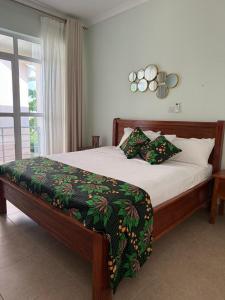 a bedroom with a large bed with a green blanket at Makucha Ya Simba Homestay and camping grounds in mwanza 